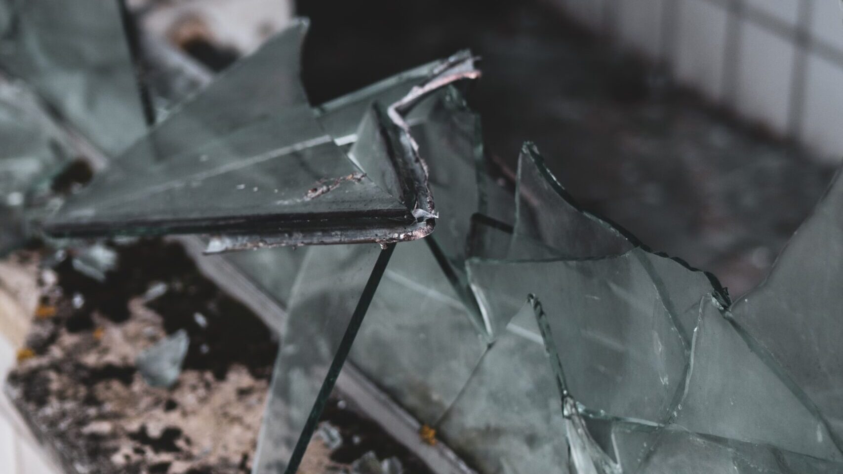 A smashed window with dangerous looking glass shards.