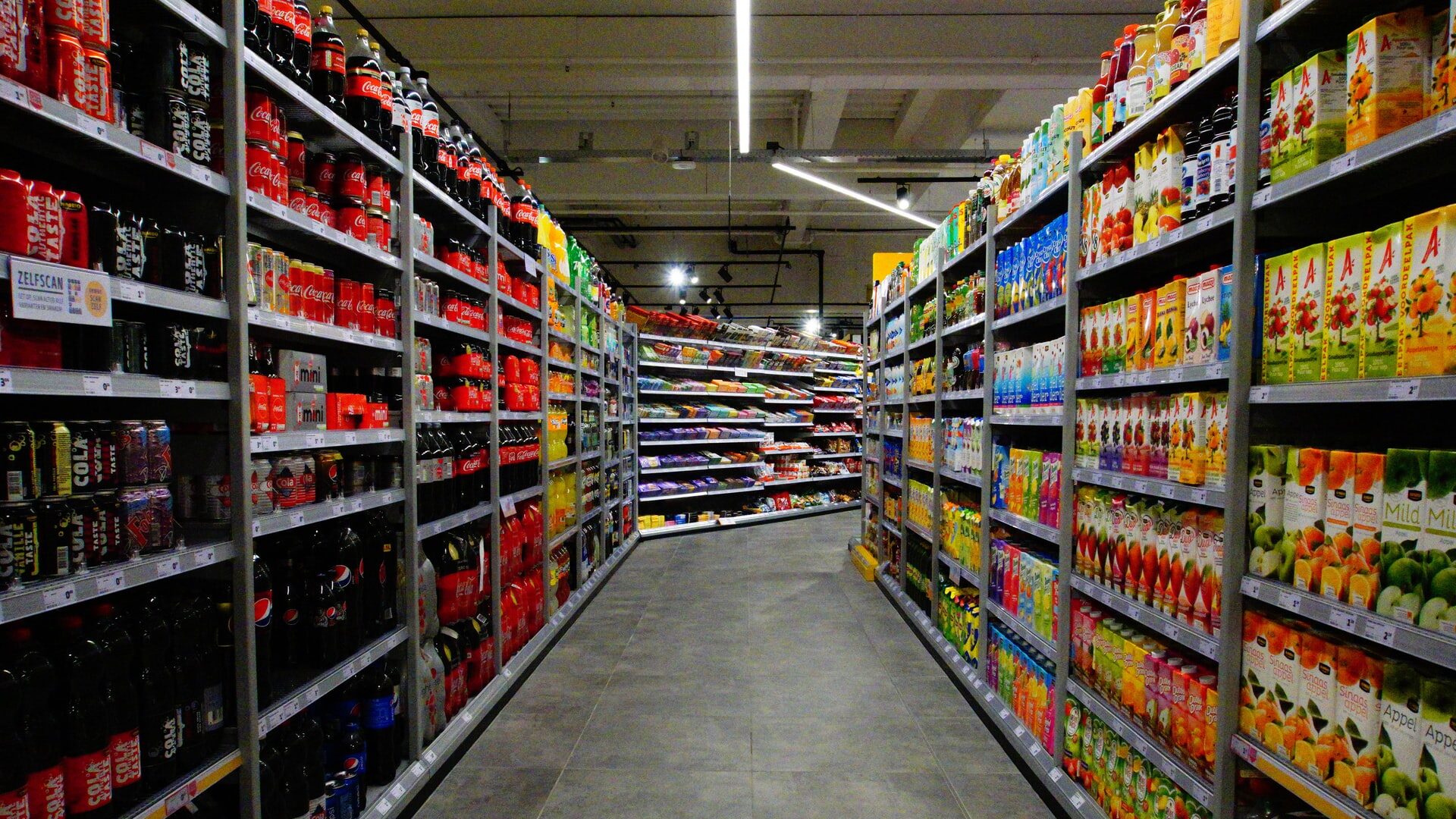 A supermarket aisle stocked with goods that turns off to the right ominously.