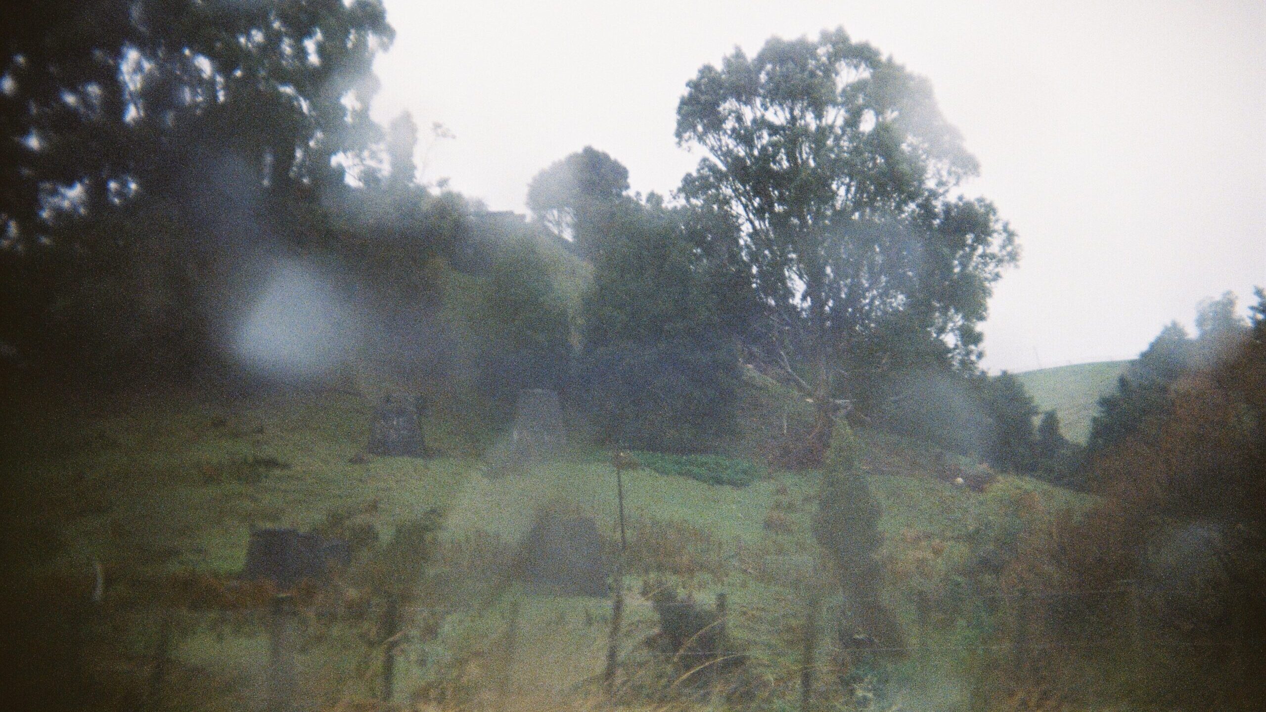 A rural scene is obscured by moisture and condensation on the lens.